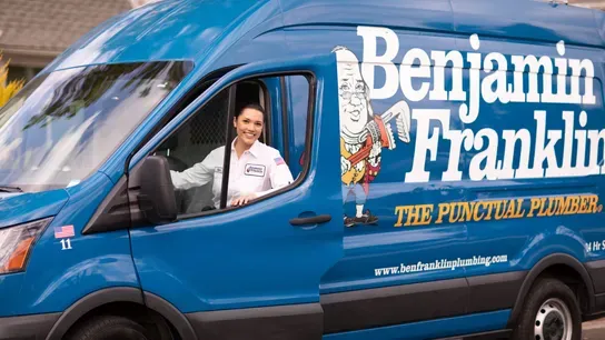 woman smiling and exiting Benjamin Franklin Plumbing van
