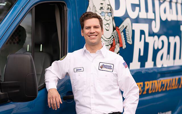 man smiling in front of Benjamin Franklin Plumbing work van